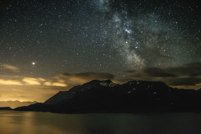 Scenic view of lake and mountains against sky at night