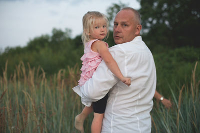 Portrait of father and daughter standing by grass