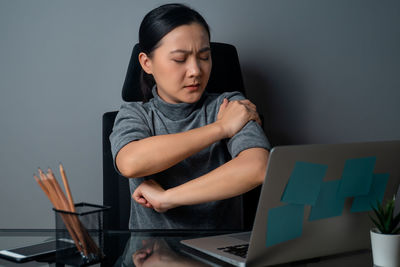 Young woman using mobile phone while sitting on table