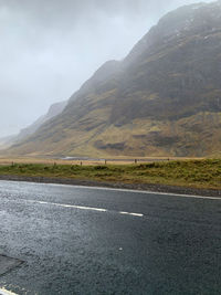 Road by mountains against sky