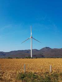 Windmill on field against blue sky