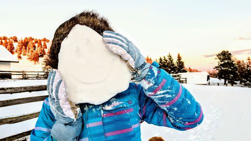 Close-up of woman holding snow while standing on field during winter