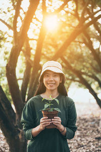 Portrait of smiling young woman standing on tree