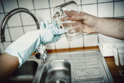 Cropped hands holding mason jar in kitchen