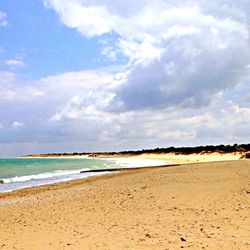 Scenic view of beach against cloudy sky
