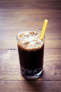 High angle view of fresh iced coffee in glass on wooden table