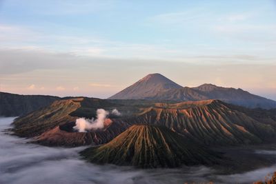 Scenic view of mountain range against sky in foggy weather