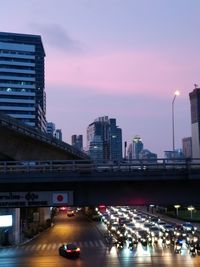 Cars on bridge in city against sky during sunset