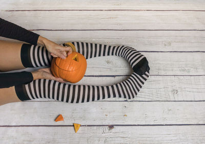 High angle view of woman holding pumpkin on table