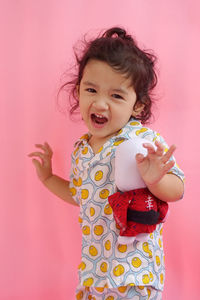 Portrait of a smiling girl standing against pink background