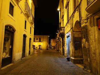 Empty alley amidst buildings in city at night