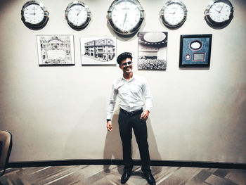 Full length portrait of young man standing against wall