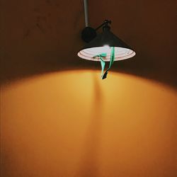 Low angle view of electric lamp hanging against wall