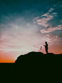 Silhouette man standing on mountain against sky during sunset