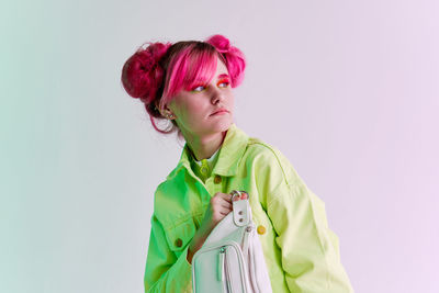 Portrait of young woman standing against white background