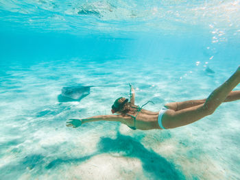 Woman swimming by stingray in sea