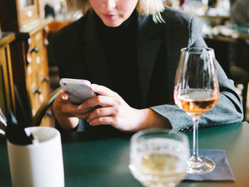 Midsection of woman using phone in restaurant