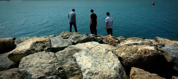 High angle view of people standing on rocks at beach