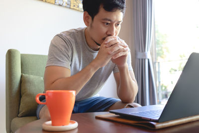 Midsection of man drinking coffee while sitting on table at home