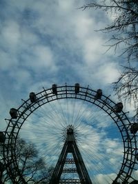 Low angle view of ferris wheel against cloudy sky