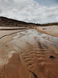 Scenic view of beach against cloudy sky