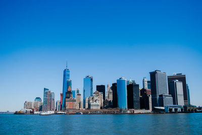 City at waterfront against blue sky