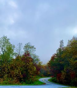 Road amidst trees against sky during autumn