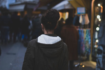 Rear view of woman standing on street at dusk