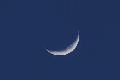 Low angle view of half moon against clear blue sky