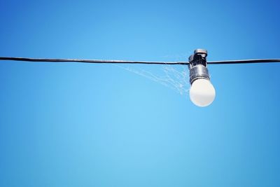 Low angle view of light bulb against clear blue sky