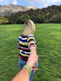 Couple holding hands on field against trees