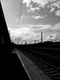 Railroad tracks against cloudy sky