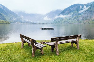 Empty benches by lake against mountains