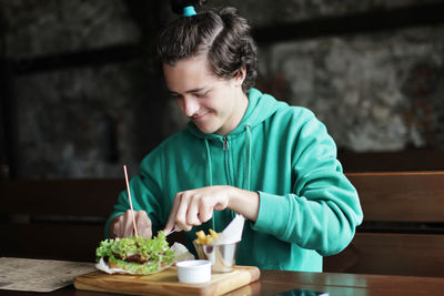 Smiling young man eating burger at restaurant