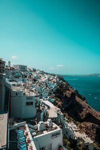 High angle view of townscape by sea against blue sky