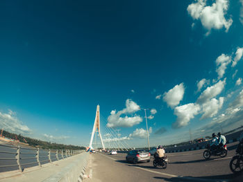 Vehicles on road against cloudy sky