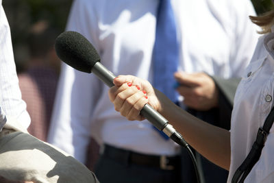 Cropped hand of journalist holding microphone for man