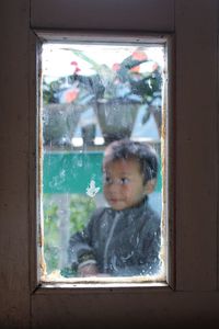 Boy seen from window glass