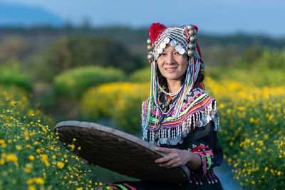 Portrait of woman standing against yellow flowers