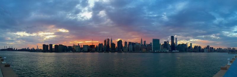 City at waterfront against cloudy sky