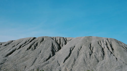 Scenic view of arid landscape against blue sky