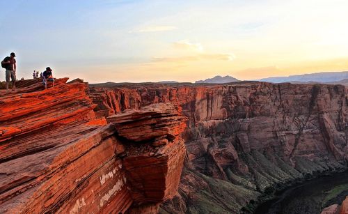 People on rock formation at horseshoe bend against sky