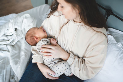 High angle view of mother with daughter sitting on bed