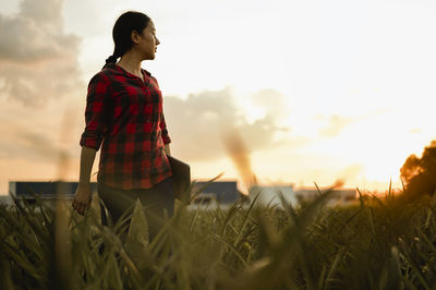 Man standing on field against sky during sunset