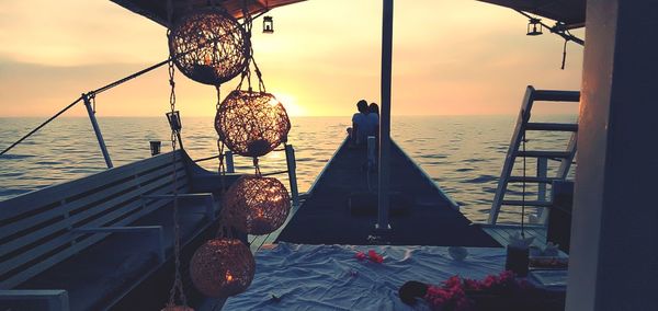 Sailboat hanging on beach against sky during sunset