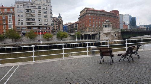 Empty benches by street against buildings in city