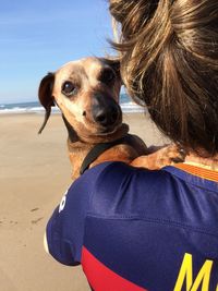 Woman with dog on beach against sky