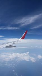 Airplane wing against cloudy sky