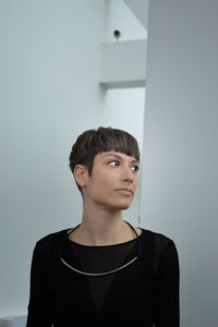 Portrait of young man looking away against wall