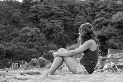 Side view of woman sitting on sand